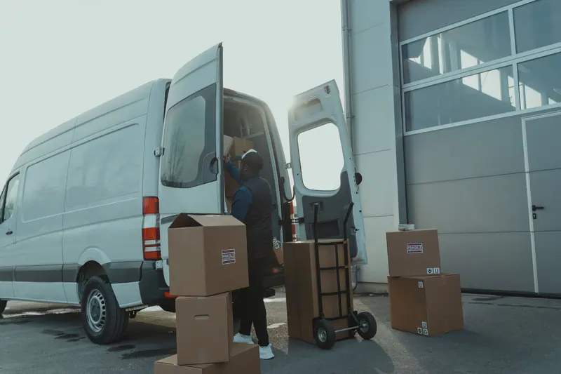 Transporter mit Kartons vor einer Halle – Möbeltransport Lemgo