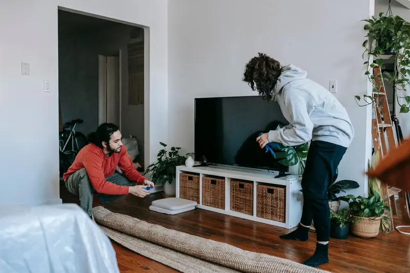 Zwei Personen räumen ein Wohnzimmer auf – Messie-Wohnung entrümpeln