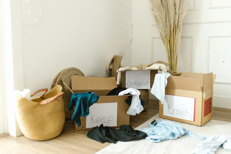 Aussortierte Kleidung und Kartons in einer hellen Wohnung – Entrümpelung