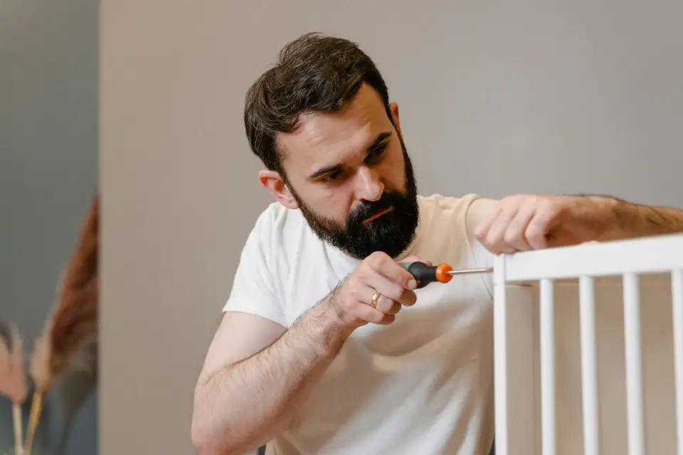 Handwerker montiert ein weißes Möbelstück mit dem Schraubendreher