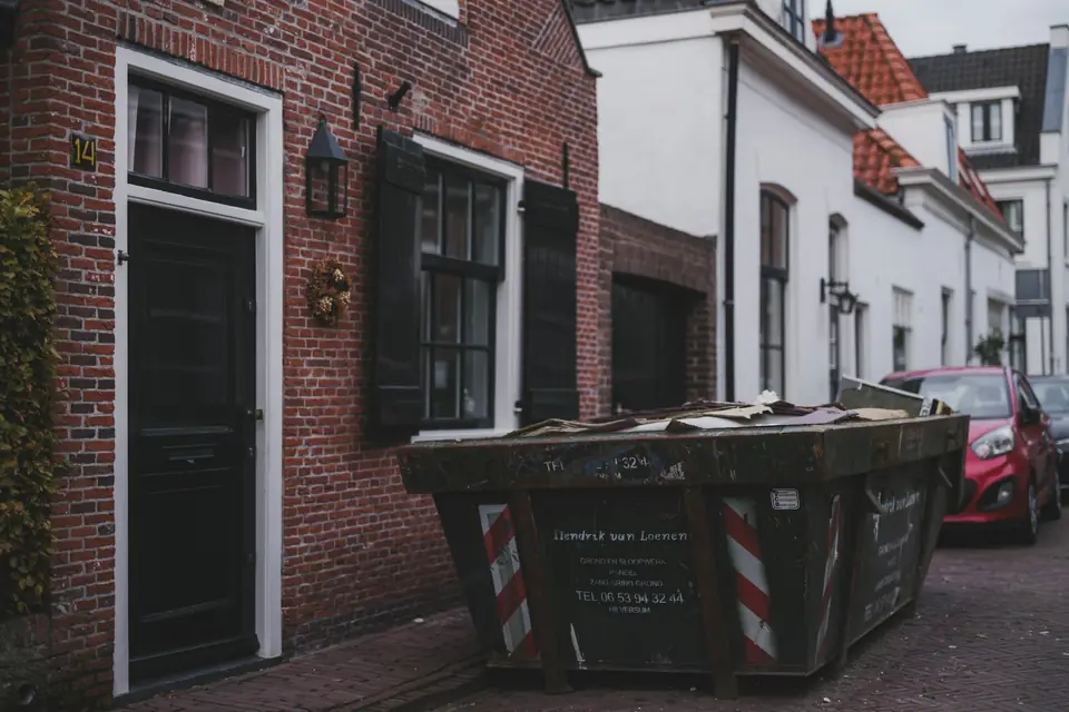 Container mit Sperrmüll in einer Straße mit Backsteinhäusern